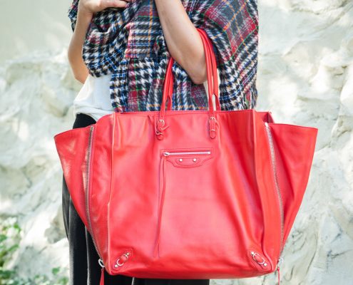 Woman holding red Balenciaga hand bag.